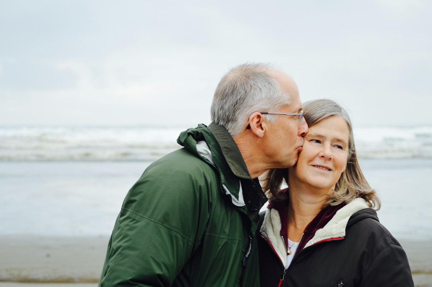 An older couple embracing outdoors, both smiling