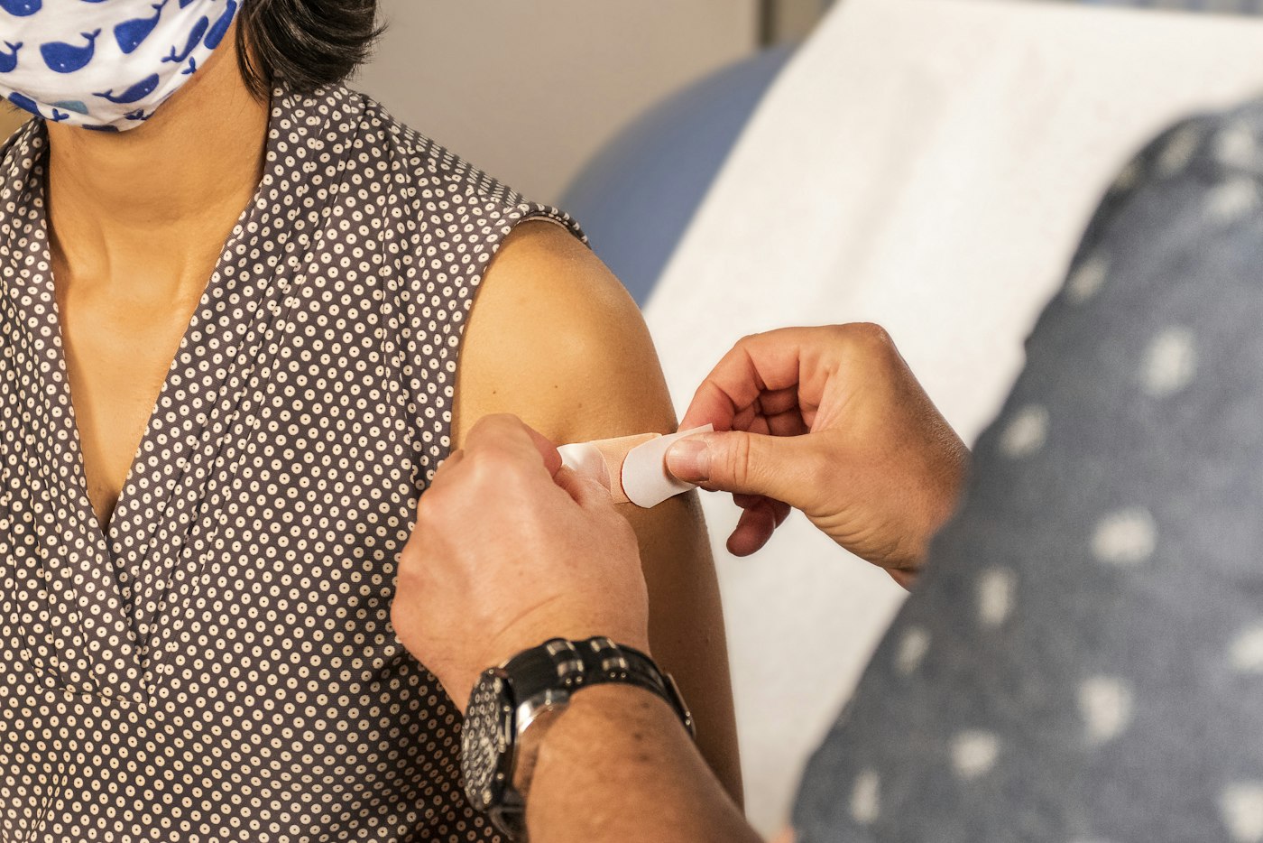 A health worker placing a small bandage on a person’s upper arm