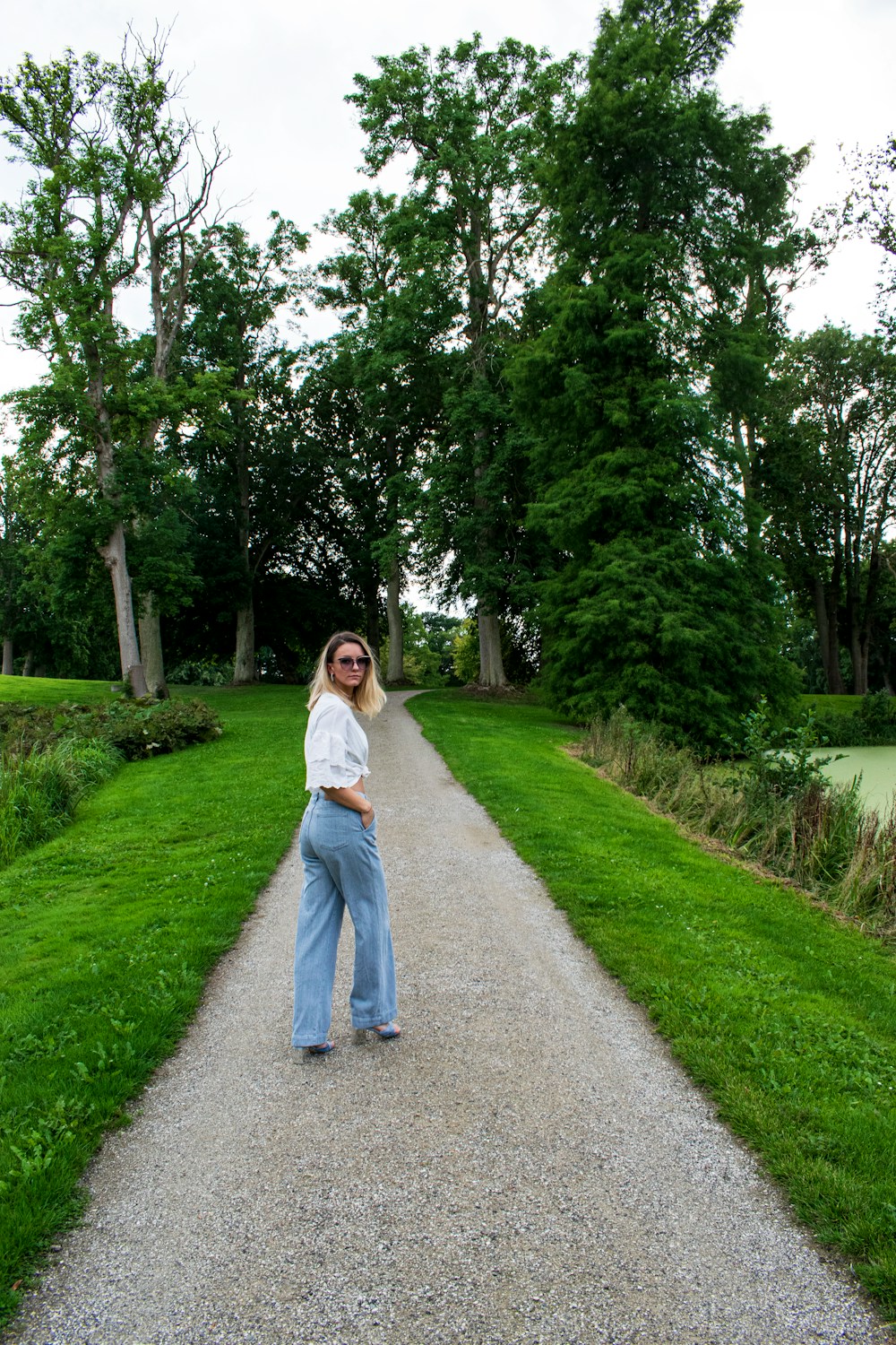 A woman walking along a path through a green park