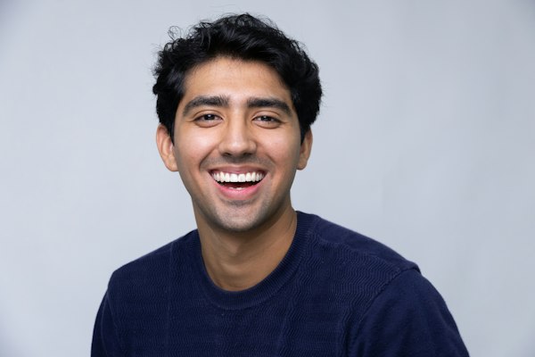 A young man in a navy sweater smiling